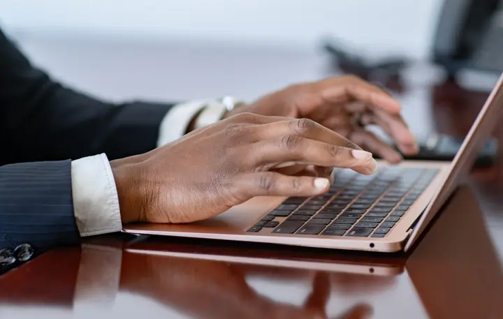 Ben's hands typing on a laptop at his desk